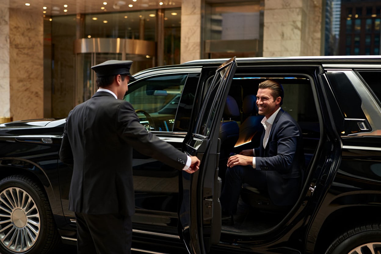 Chauffeur opening the door of a black SUV for a guest at a hotel